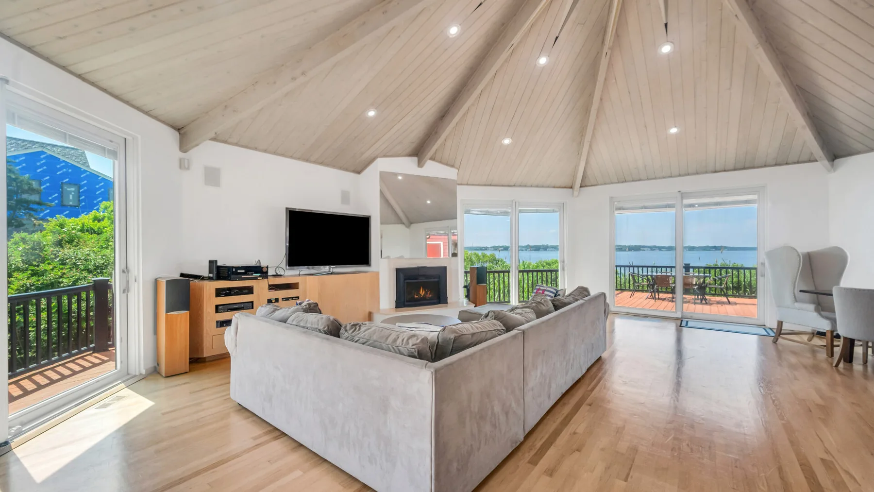 Una sala luminosa con asientos, una chimenea y grandes ventanas con vistas a la vegetación y al agua.