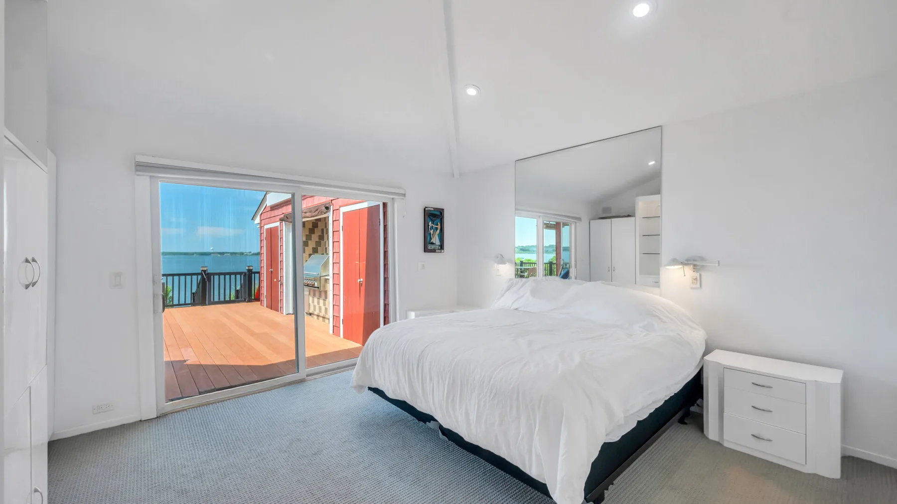 Un dormitorio luminoso con una cama grande junto a puertas corredizas de vidrio que dan a una terraza.