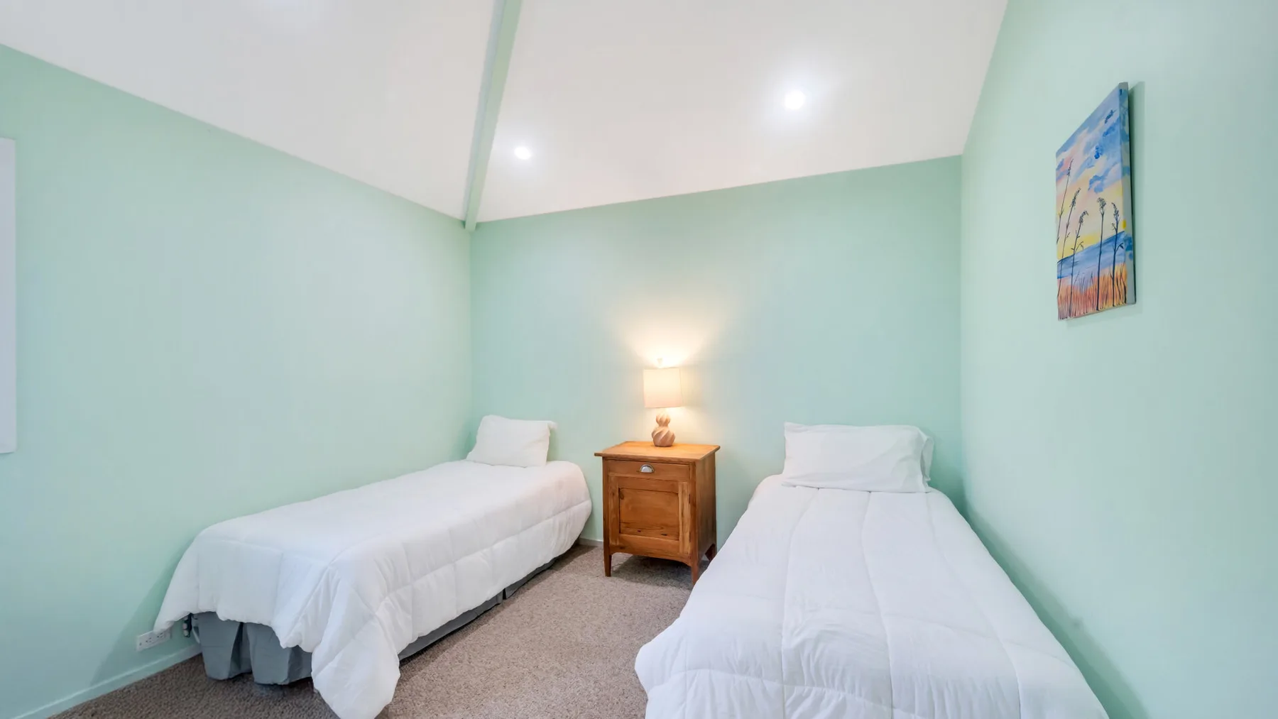 Un dormitorio con dos camas individuales y una mesita de madera entre ellas.