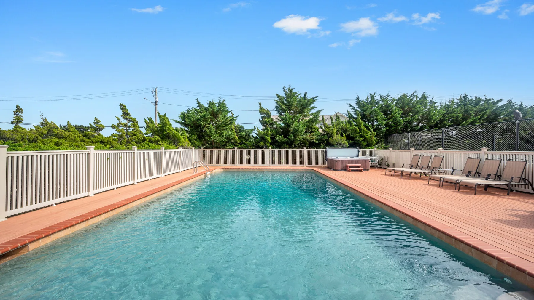 Una piscina al aire libre está rodeada por una terraza y asientos.