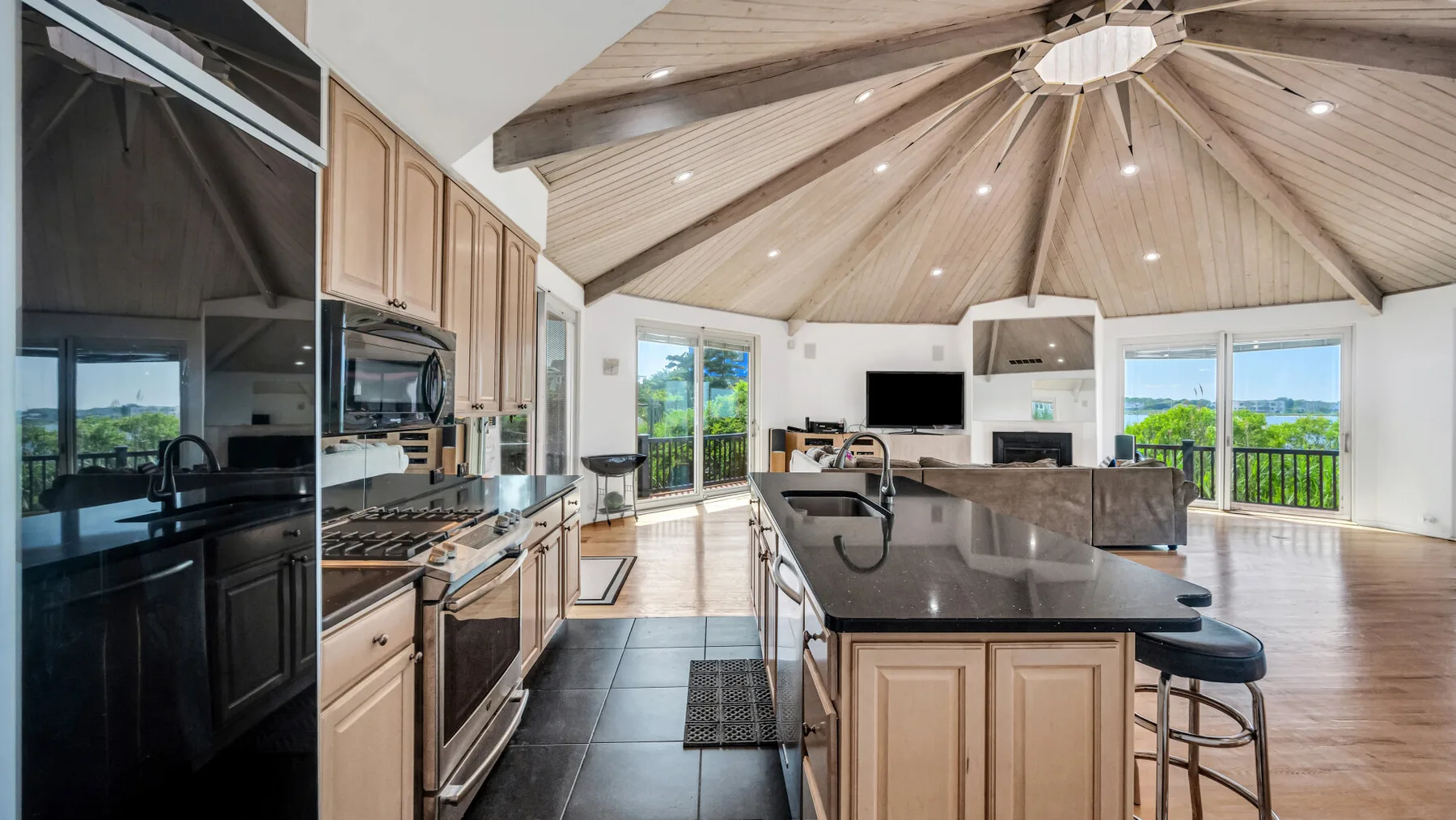 Una cocina luminosa con una isla central se abre a una sala de estar y grandes ventanales.