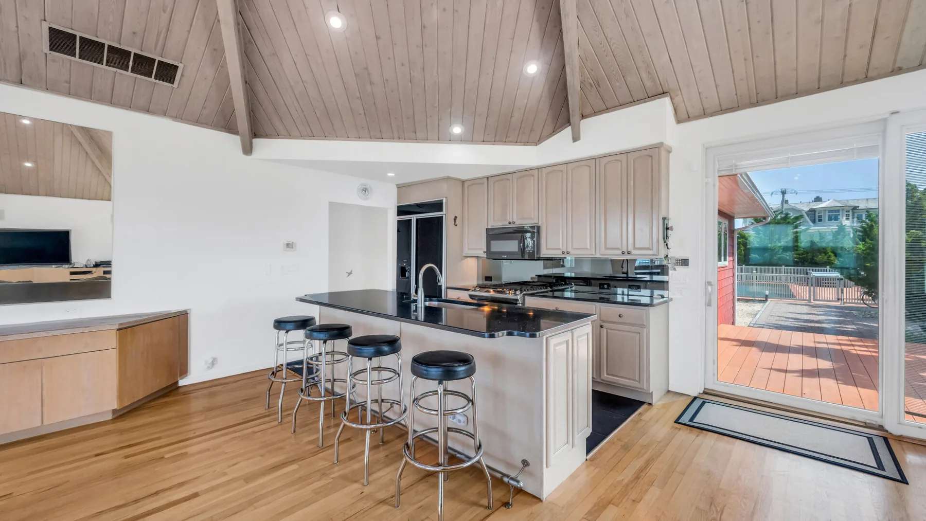Una cocina luminosa con una isla central y puertas corredizas de vidrio que dan a una terraza.