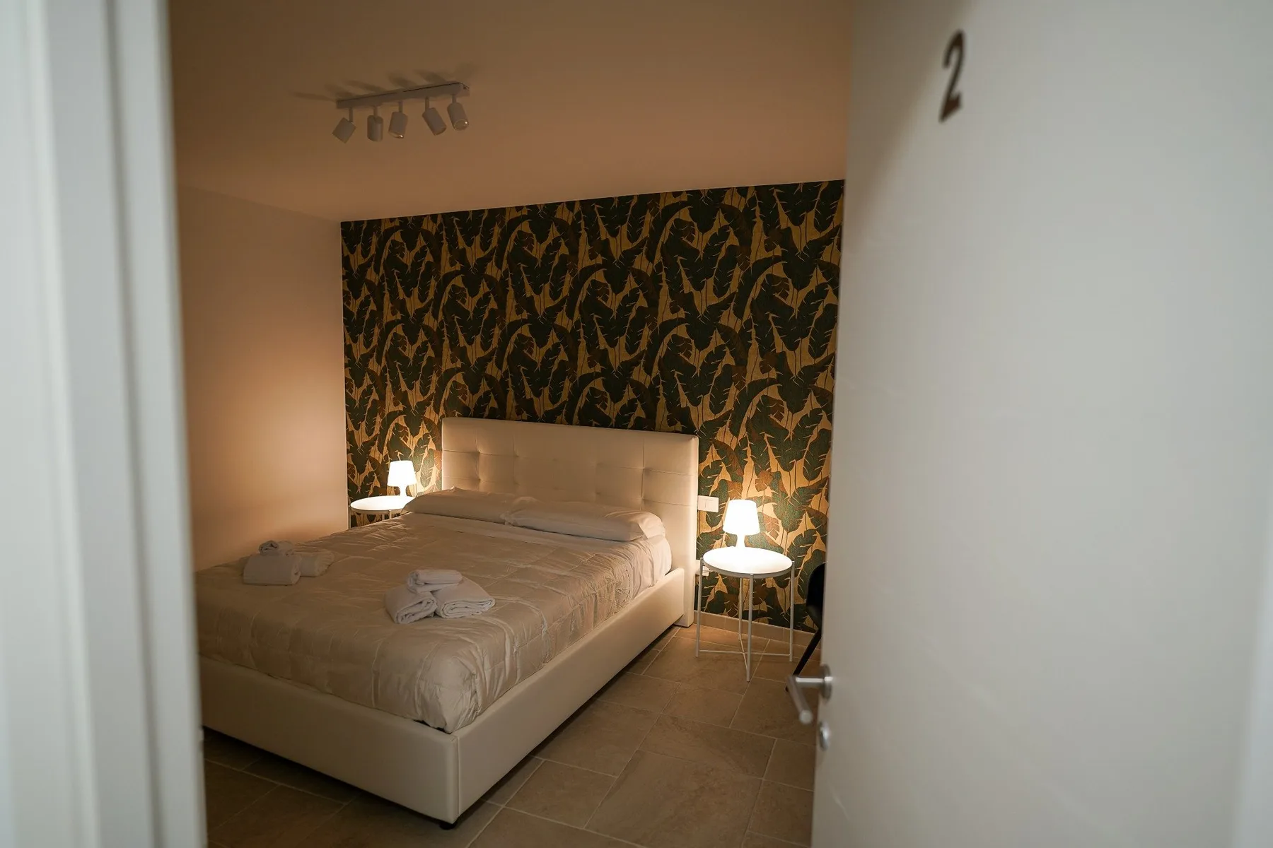 Un dormitorio con una cama frente a una pared decorativa estampada.