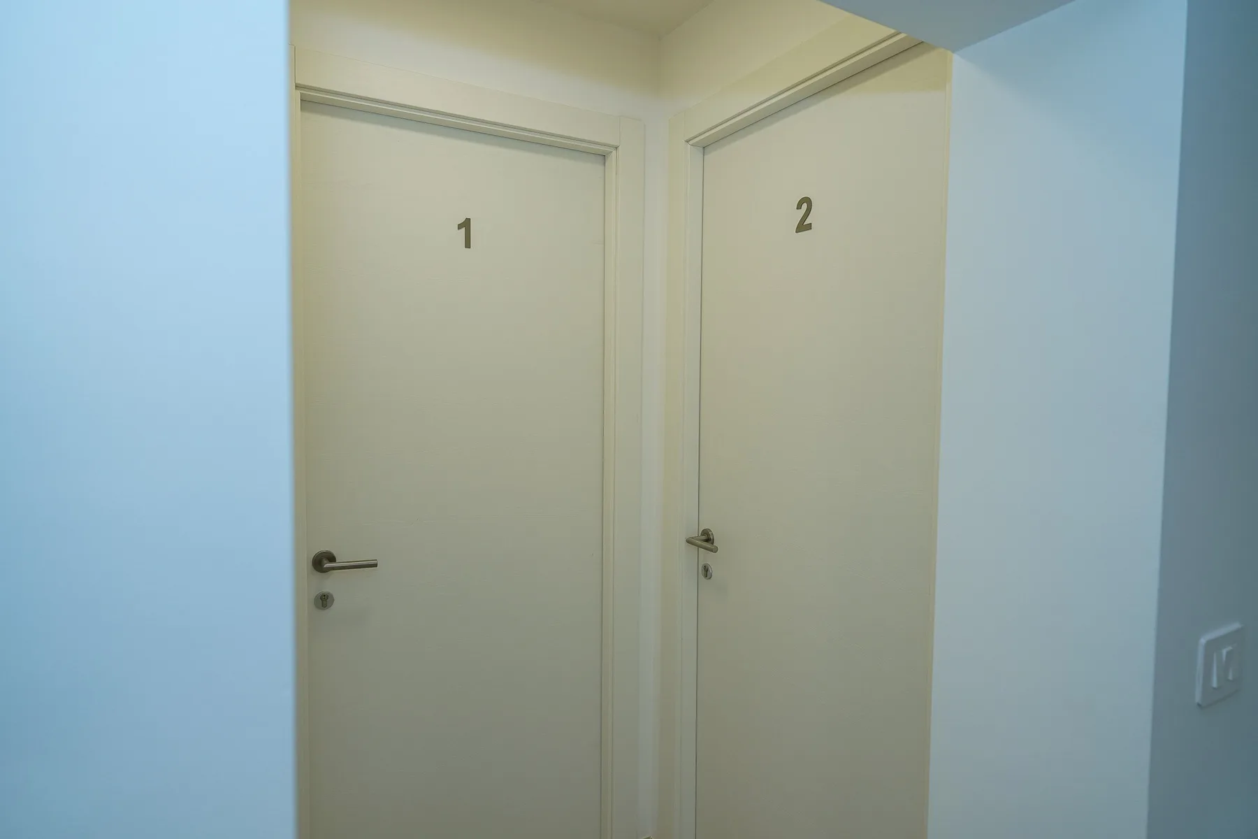 Un pasillo interior con dos puertas cerradas marcadas con números.