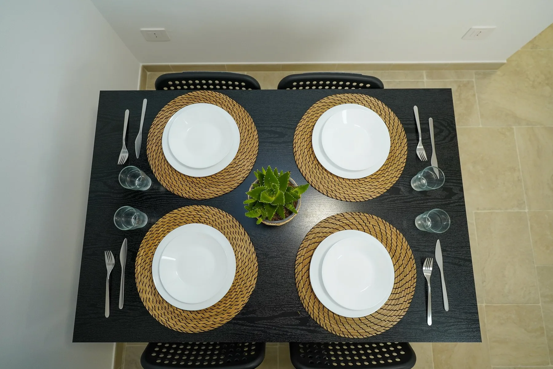 Una mesa de comedor está puesta con cuatro servicios y vasos.