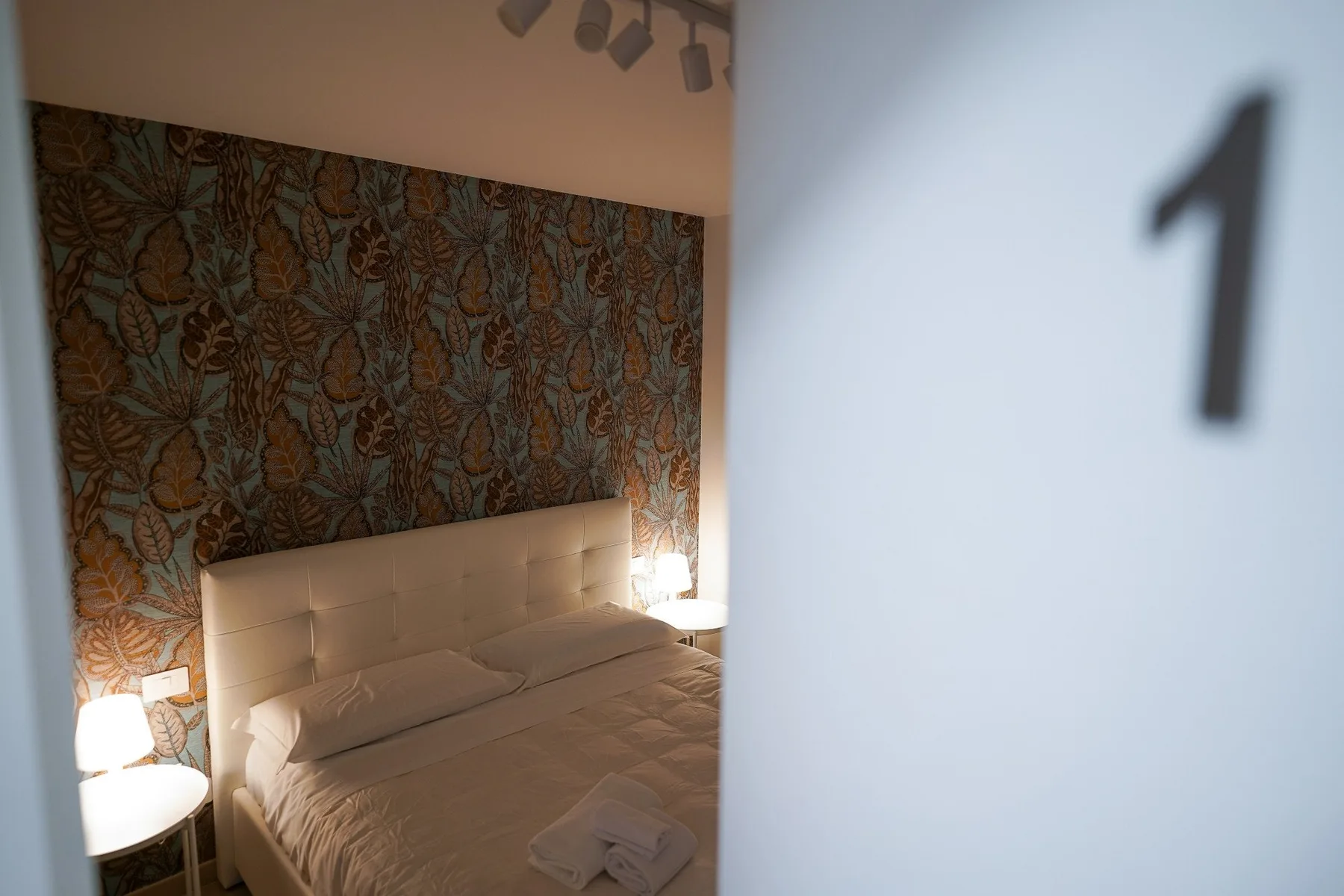 Un dormitorio con una cama frente a una pared estampada.