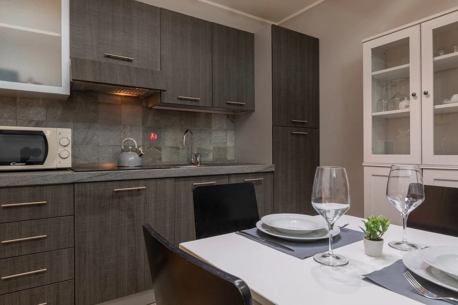 A modern kitchen and dining area with dark cabinets and a set table.