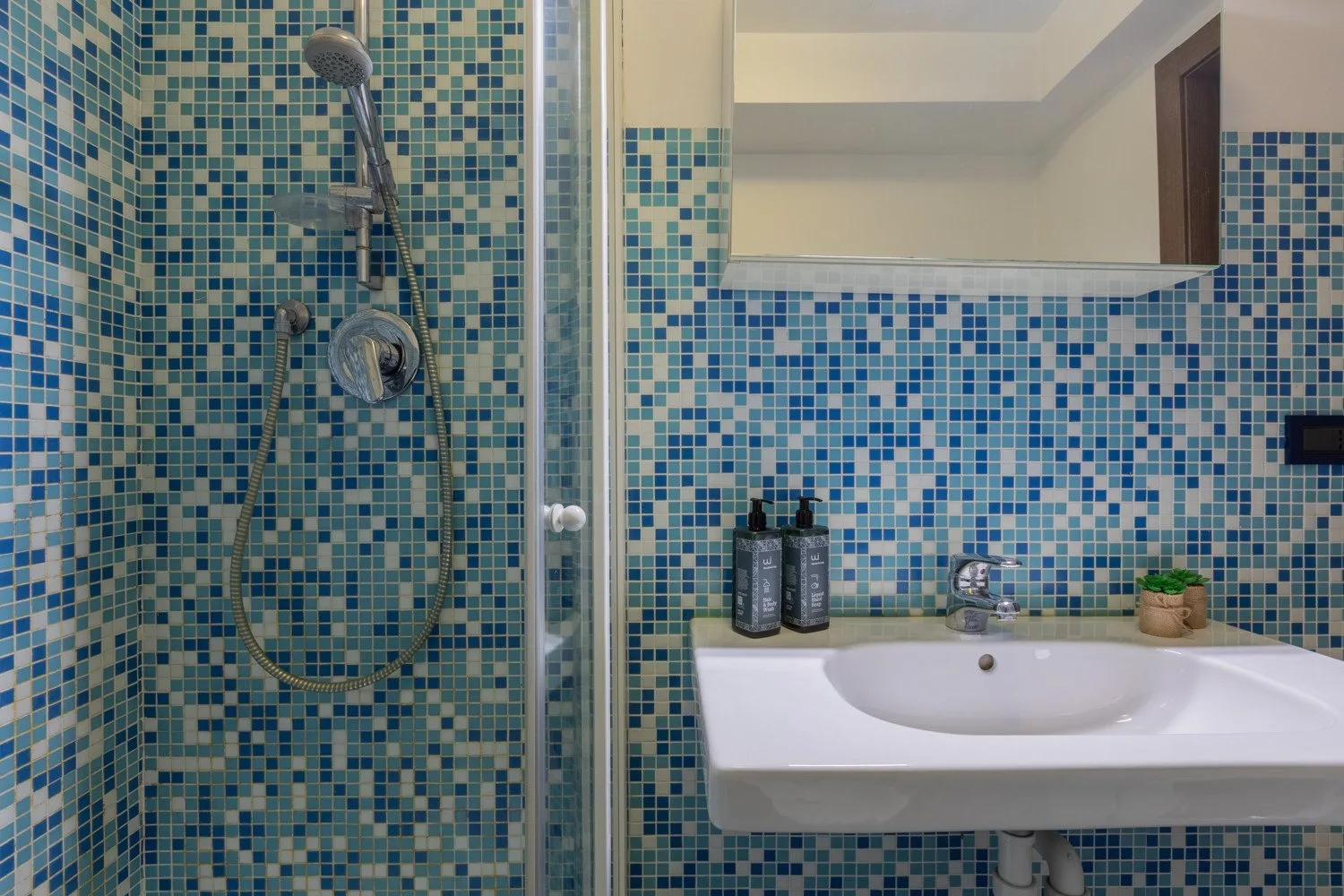 A tiled bathroom with a shower and white sink.