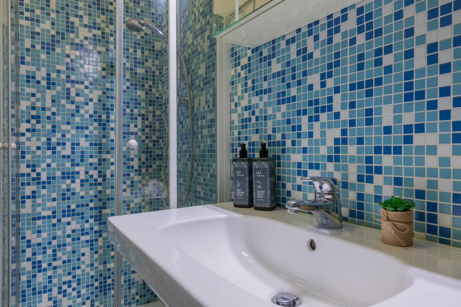 A tiled bathroom with a white sink and small potted plant.