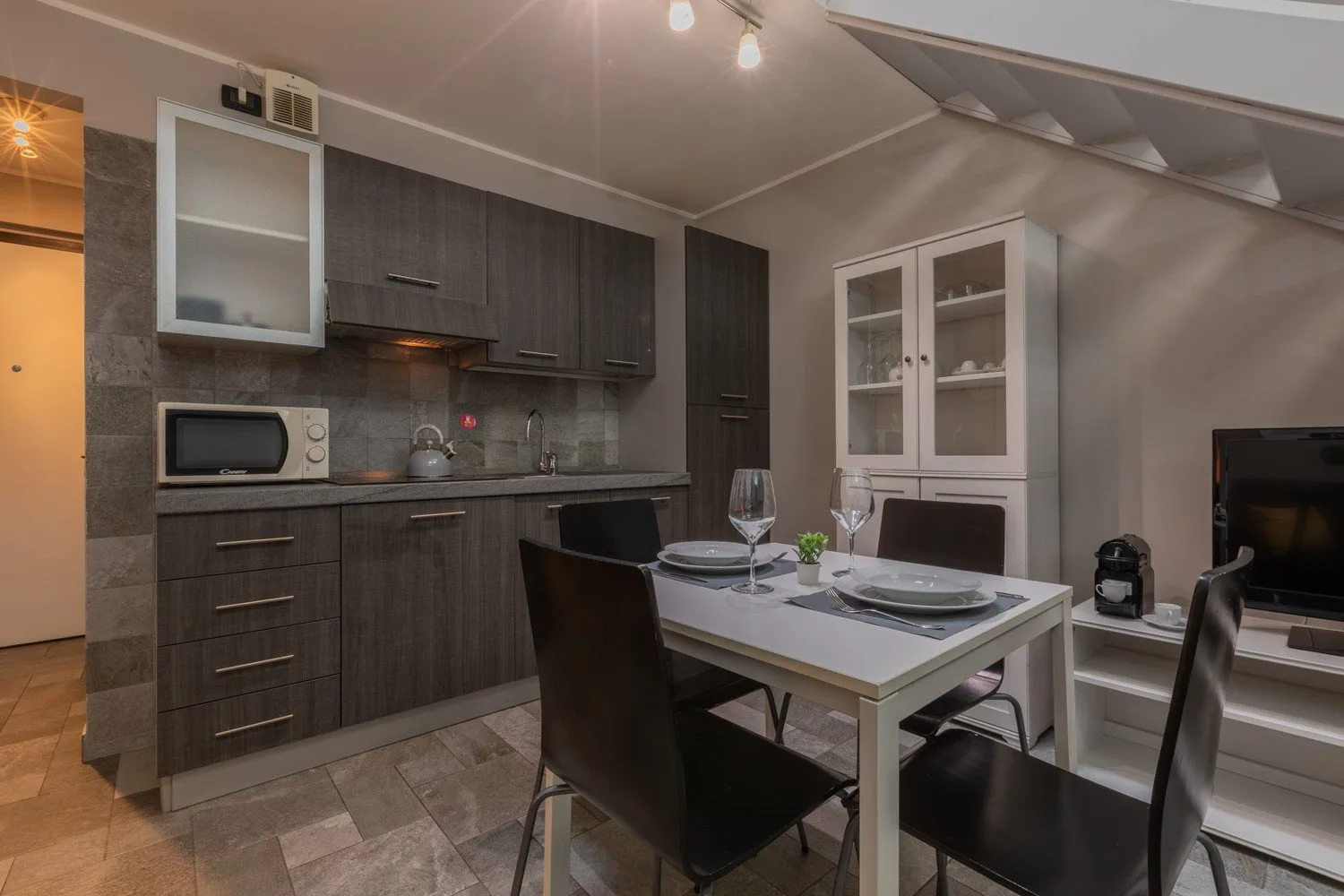 A kitchen and dining area with dark cabinetry, a table, and chairs.