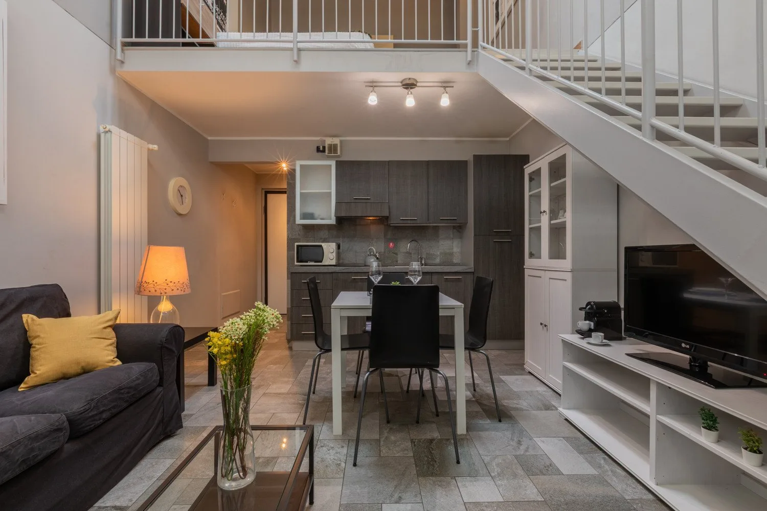 An open-plan living and dining area with a staircase and television.