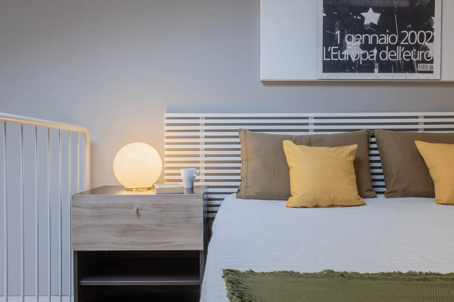 A bedroom with a neatly made bed, accent pillows, and a bedside table.