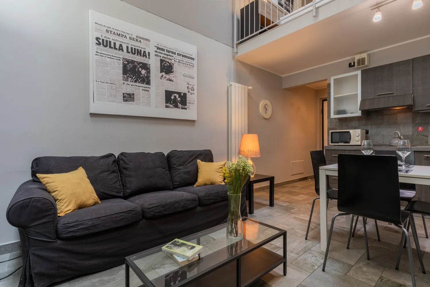 A living and dining area with dark seating, a glass coffee table, and a dining table.