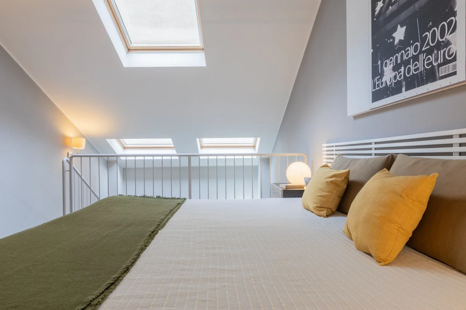 A bright loft bedroom with a bed beneath skylights.