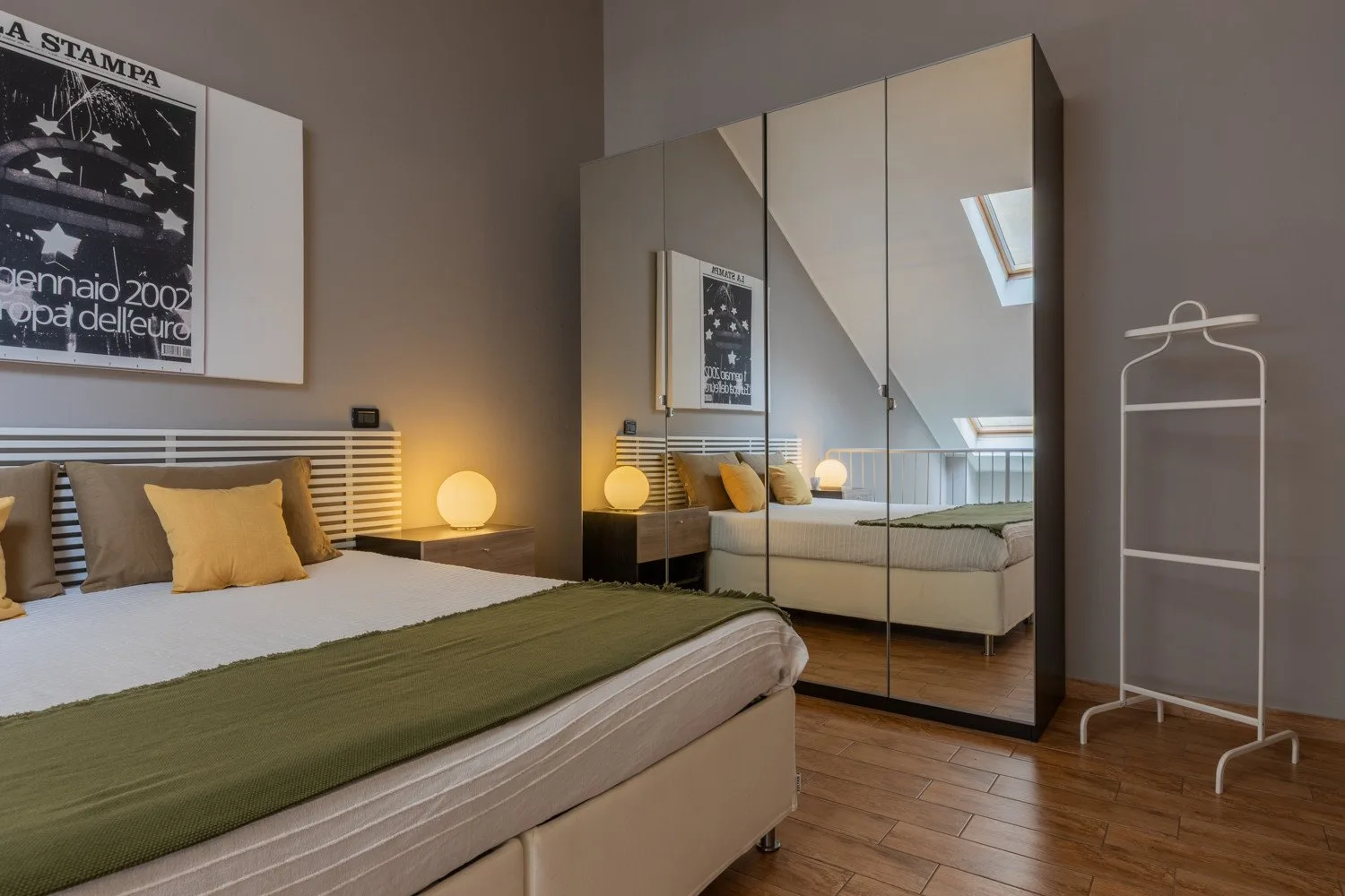 A bedroom with a bed, mirrored wardrobe, and bedside lamps.