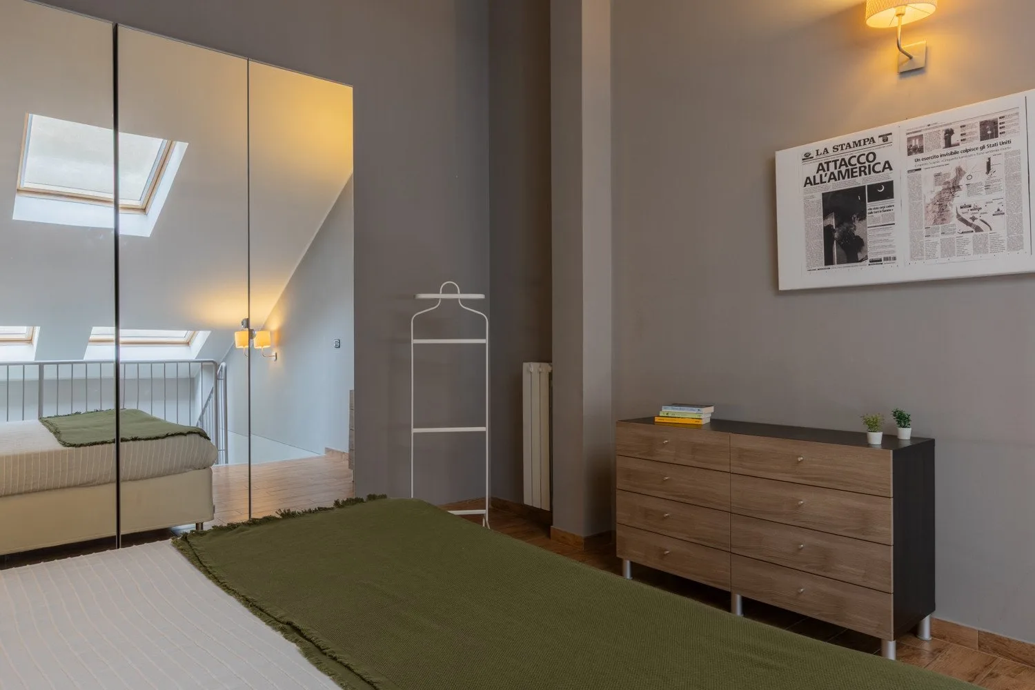 A bedroom with a low bed, mirrored wardrobe, and wooden dresser.