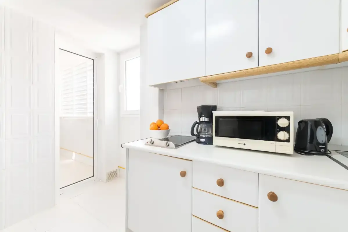 A bright kitchen with white cabinets and countertop appliances.