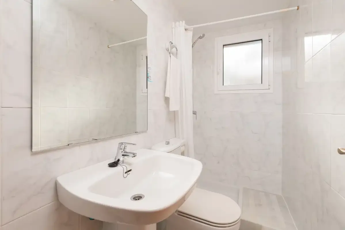 A bright bathroom with a sink, mirror, and window.