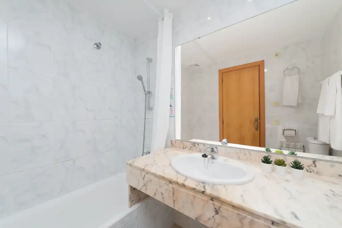 A bright bathroom with a sink beside a shower.