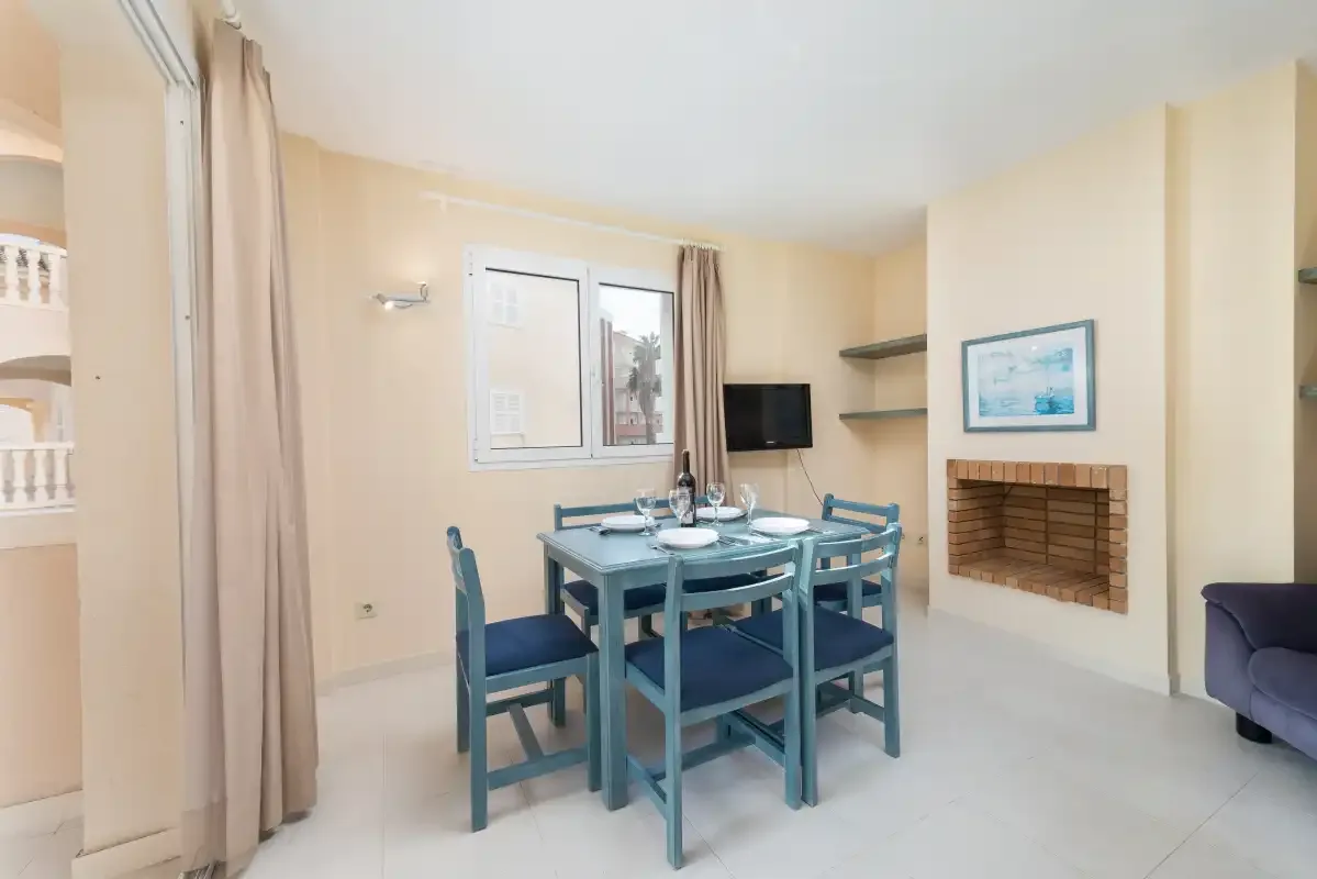 A dining area with a blue table and chairs beside a window.