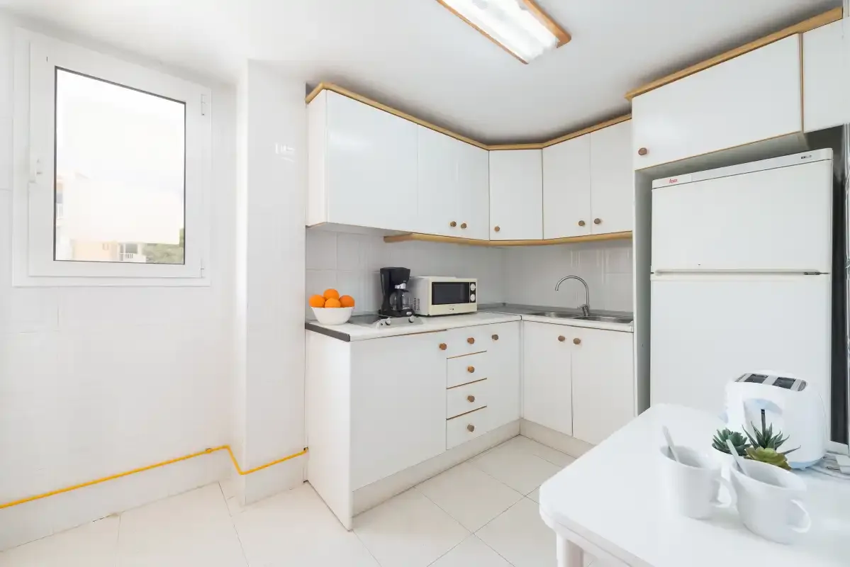 A bright kitchen with white cabinets, a countertop, and a small dining table.
