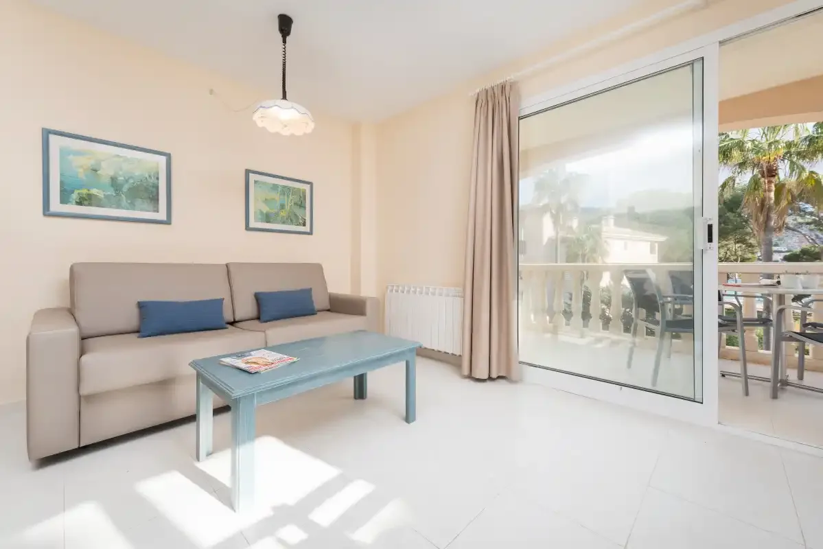 A bright living room with seating, a coffee table, and sliding glass doors to a balcony.