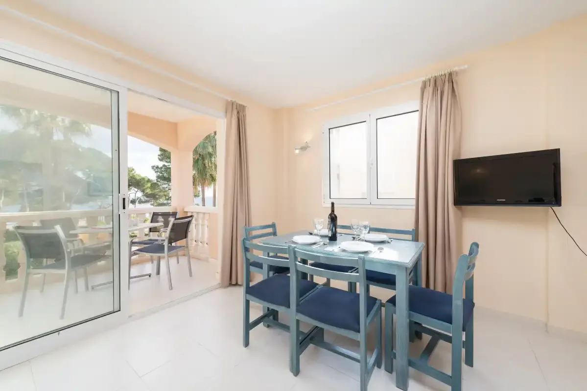 A dining area with a table and chairs beside a sliding glass door.