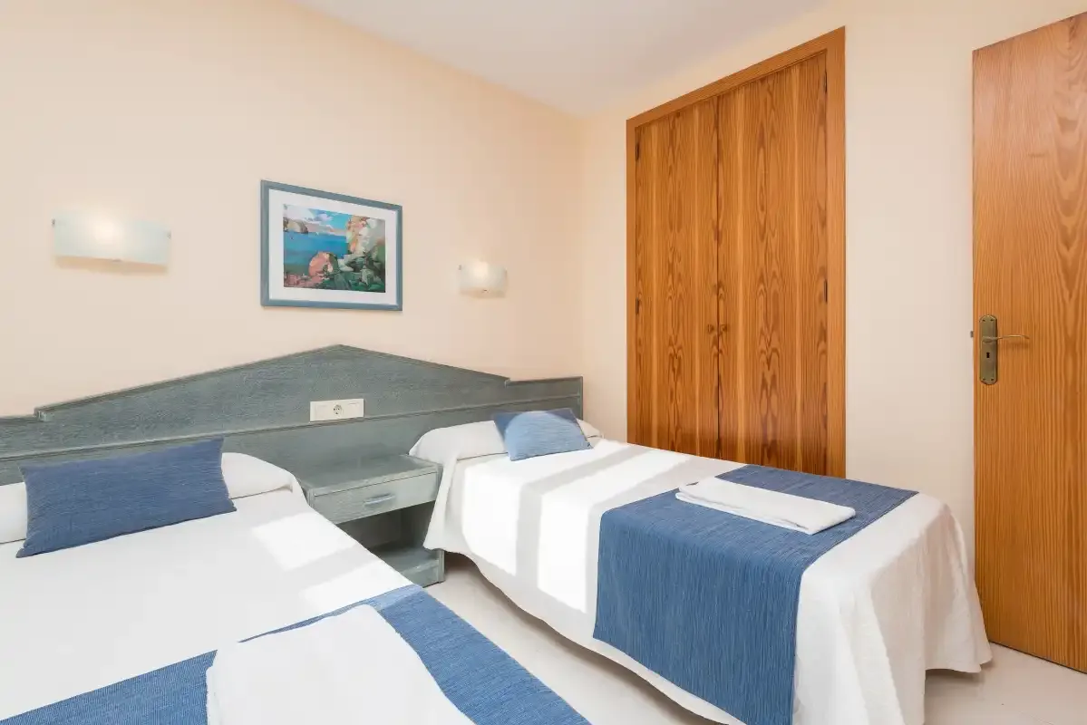 A bedroom with two single beds, blue accents, and wooden doors.