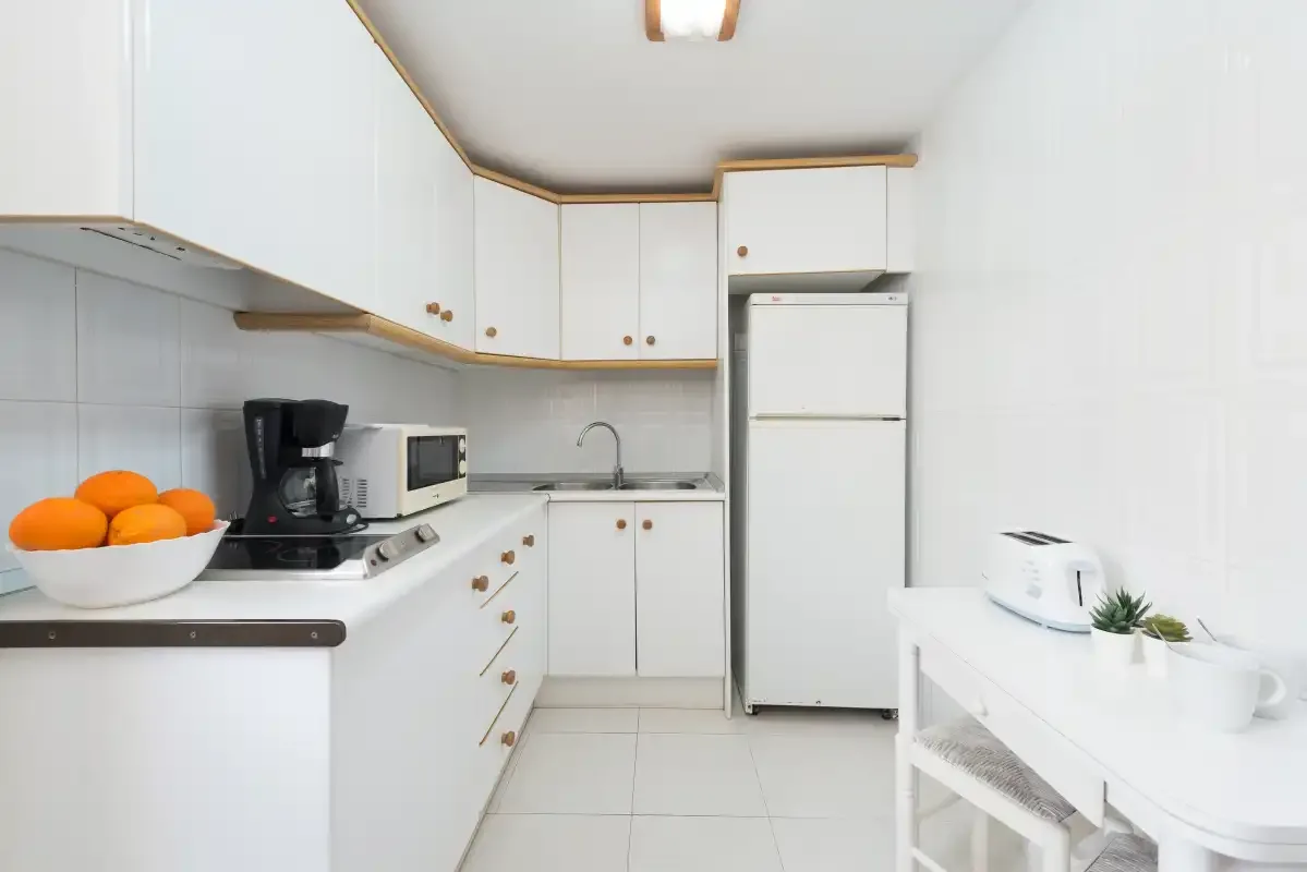 A bright kitchen with white cabinets and a countertop holding small appliances.