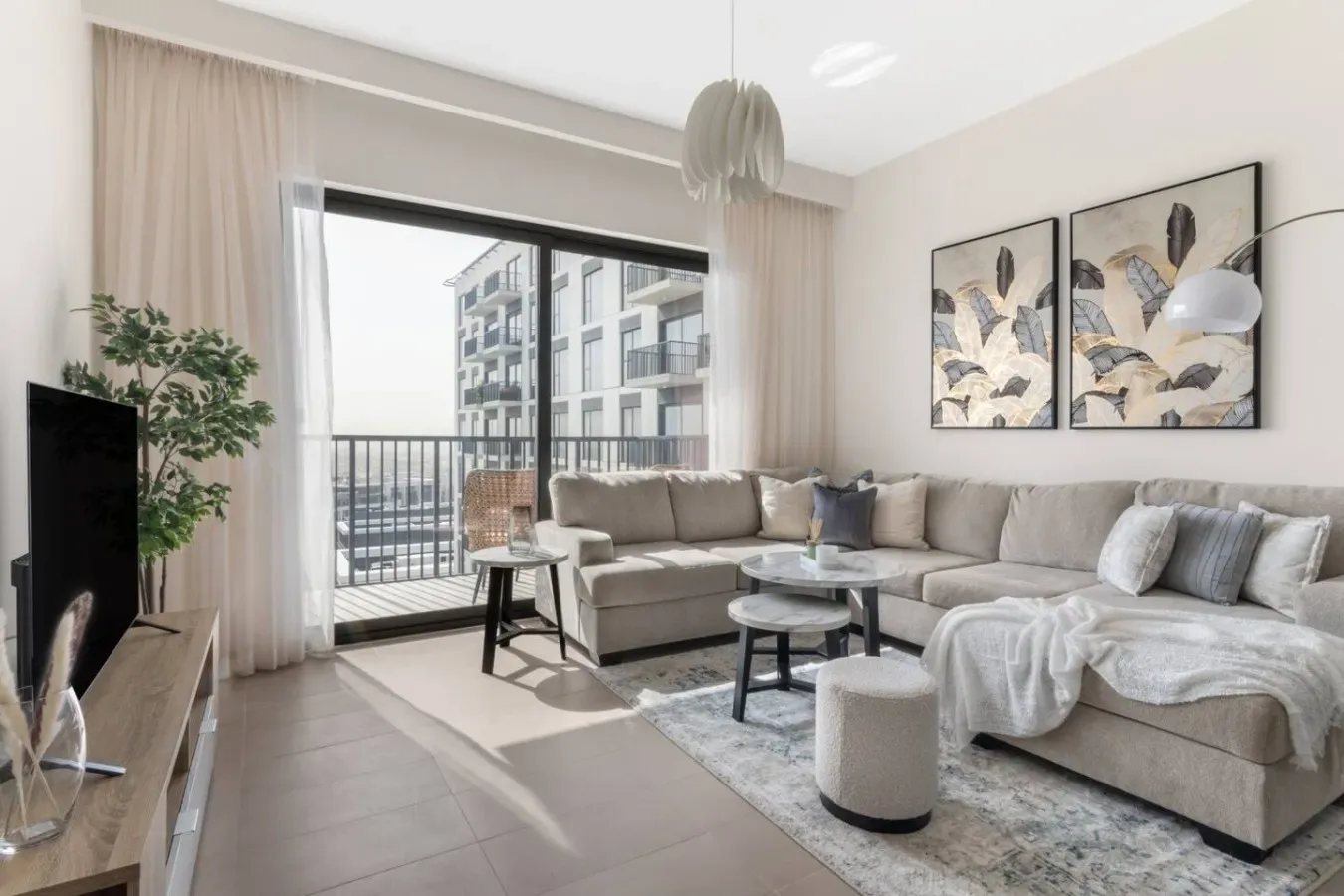 Una sala luminosa con una zona de asientos junto a una puerta de vidrio al balcón.