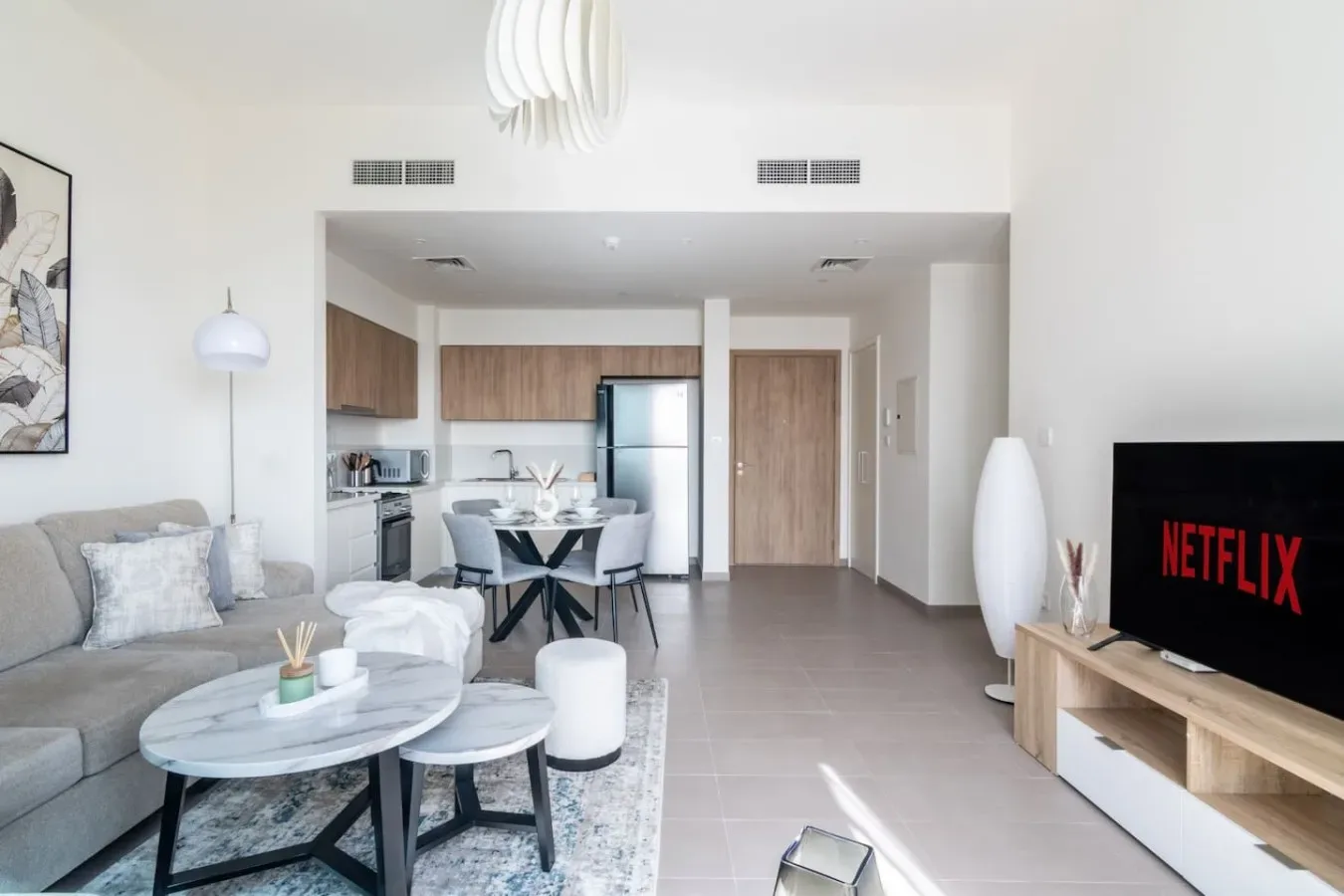 A bright open-plan living room with seating and a dining area beside the kitchen.