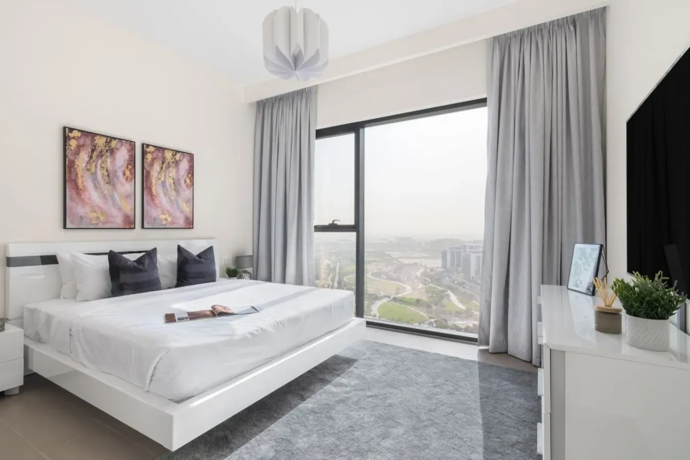 A bright bedroom with a neatly made bed beside a large window.