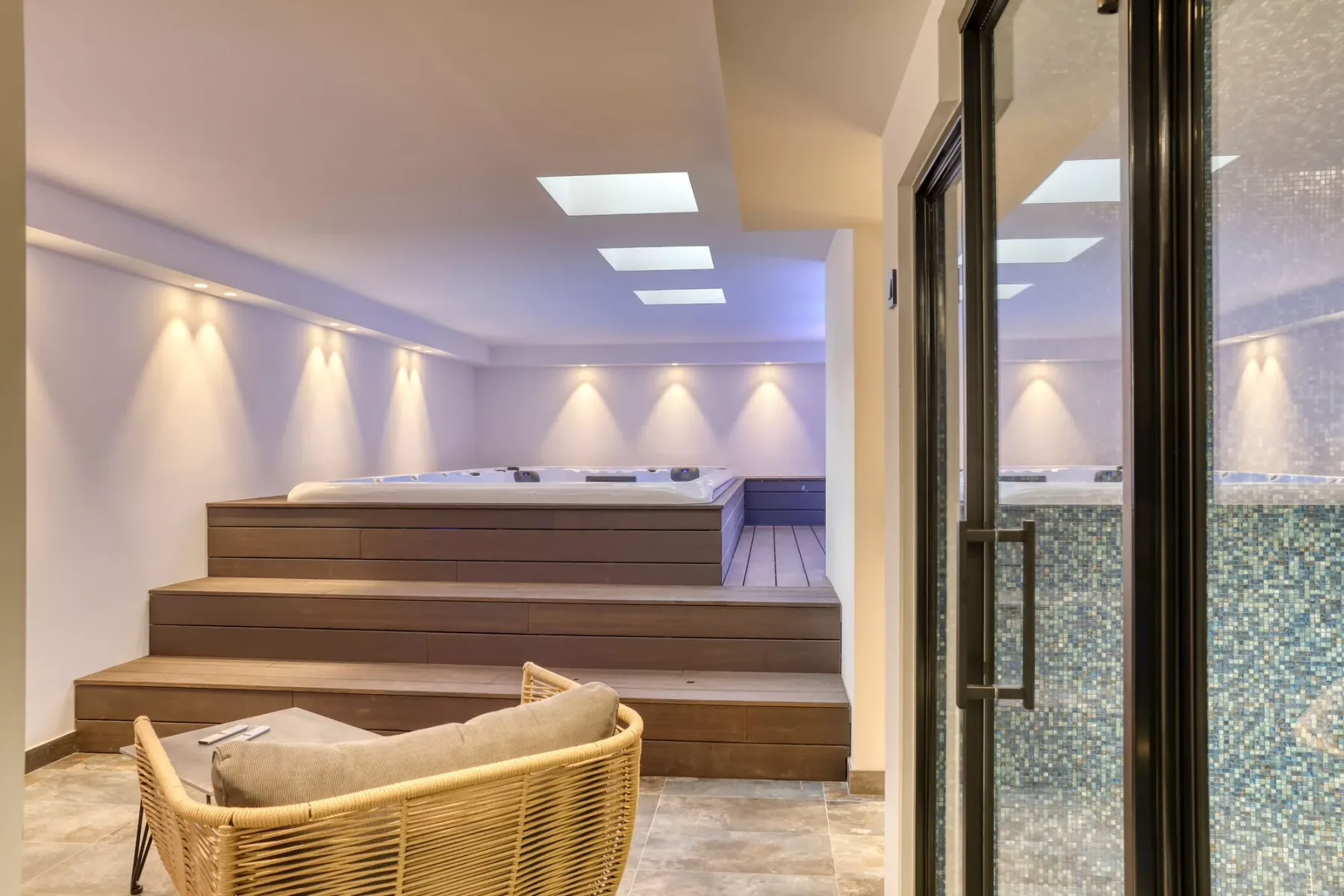 A spa room with a raised hot tub and wicker seating.