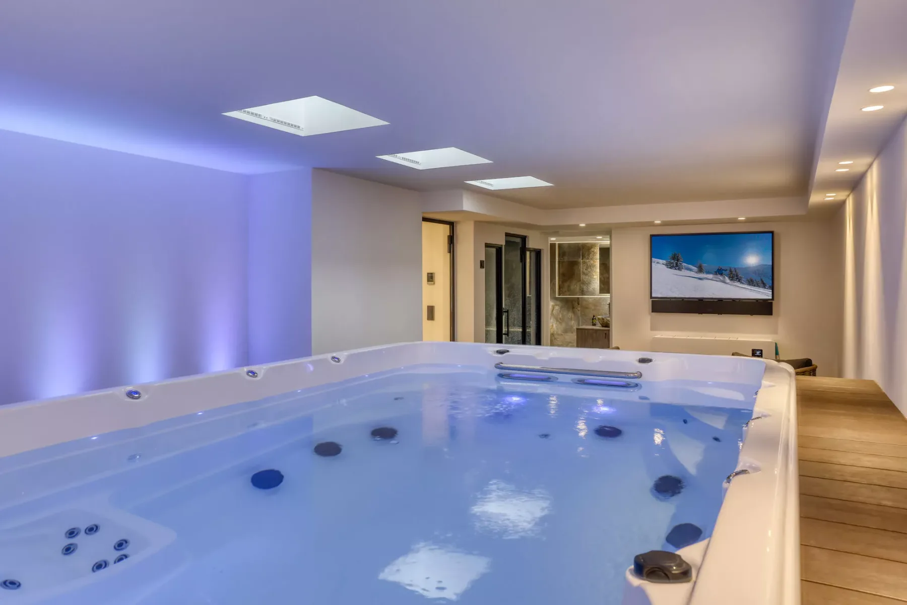 An indoor spa room features a large whirlpool tub and a wall-mounted television.