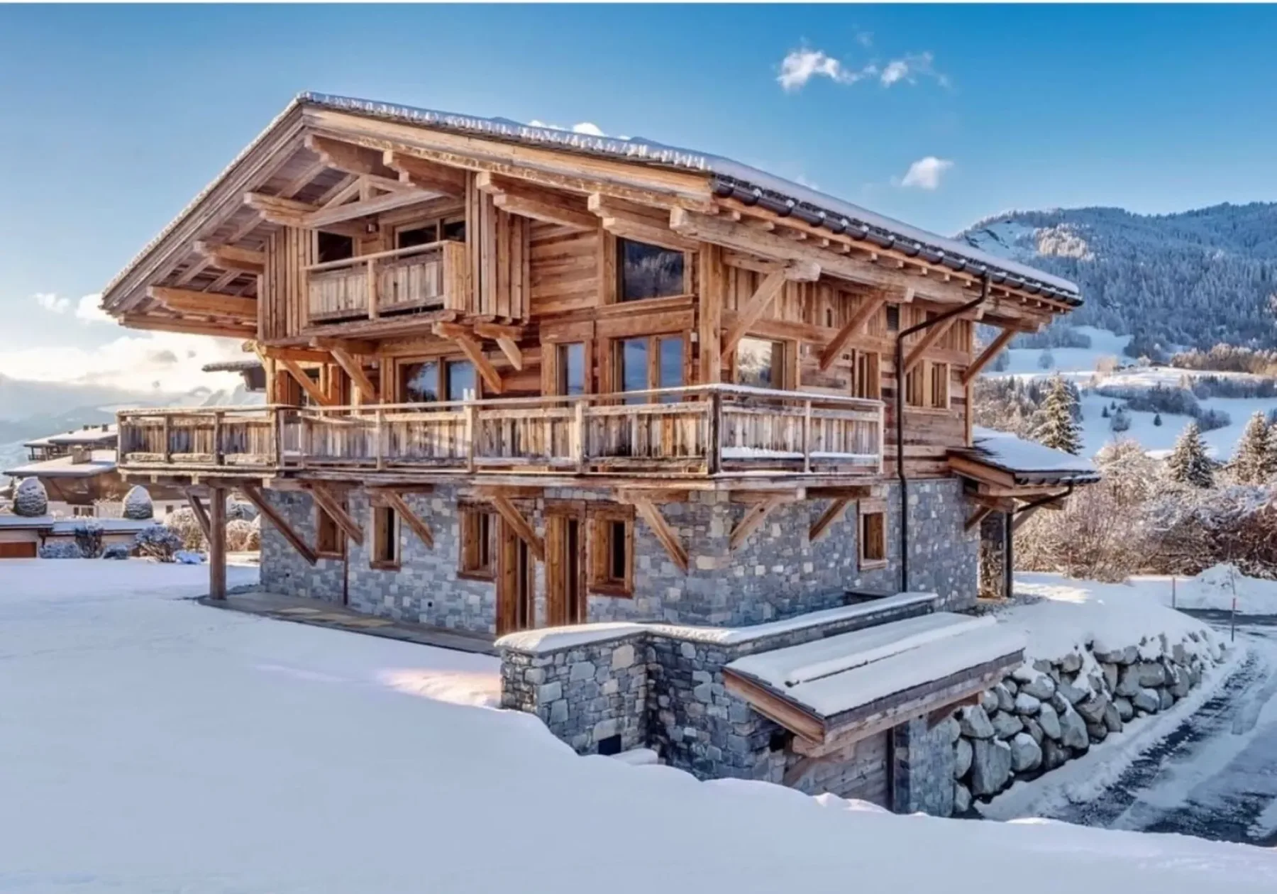 A large timber-and-stone chalet stands in a snowy mountain landscape.