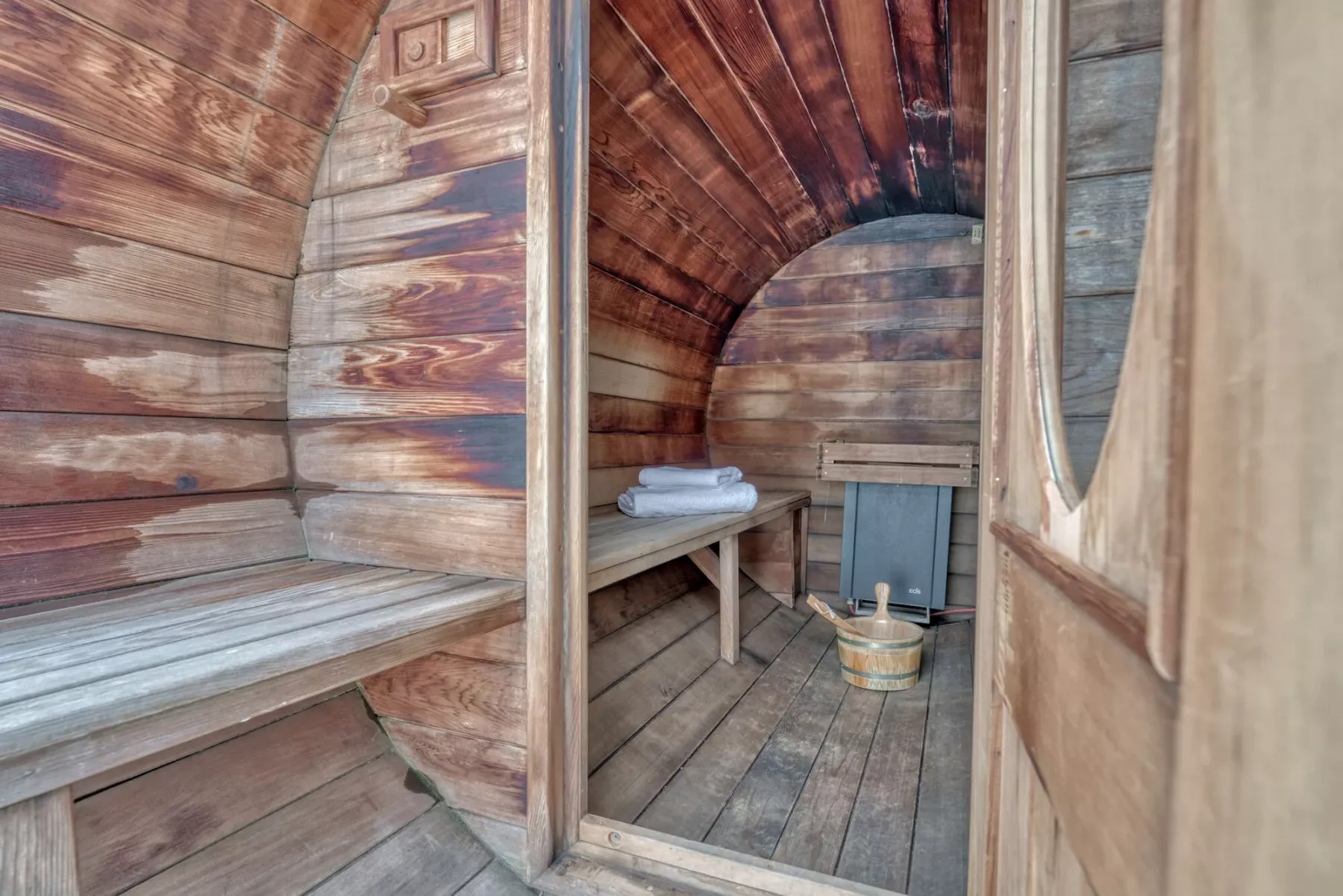 A wood-paneled sauna room with a bench and folded towels.