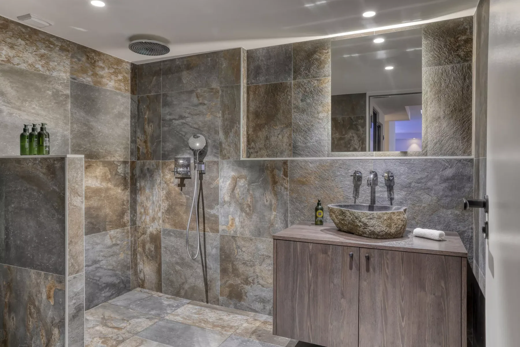 A tiled bathroom with a vanity, sink, and shower fixtures.