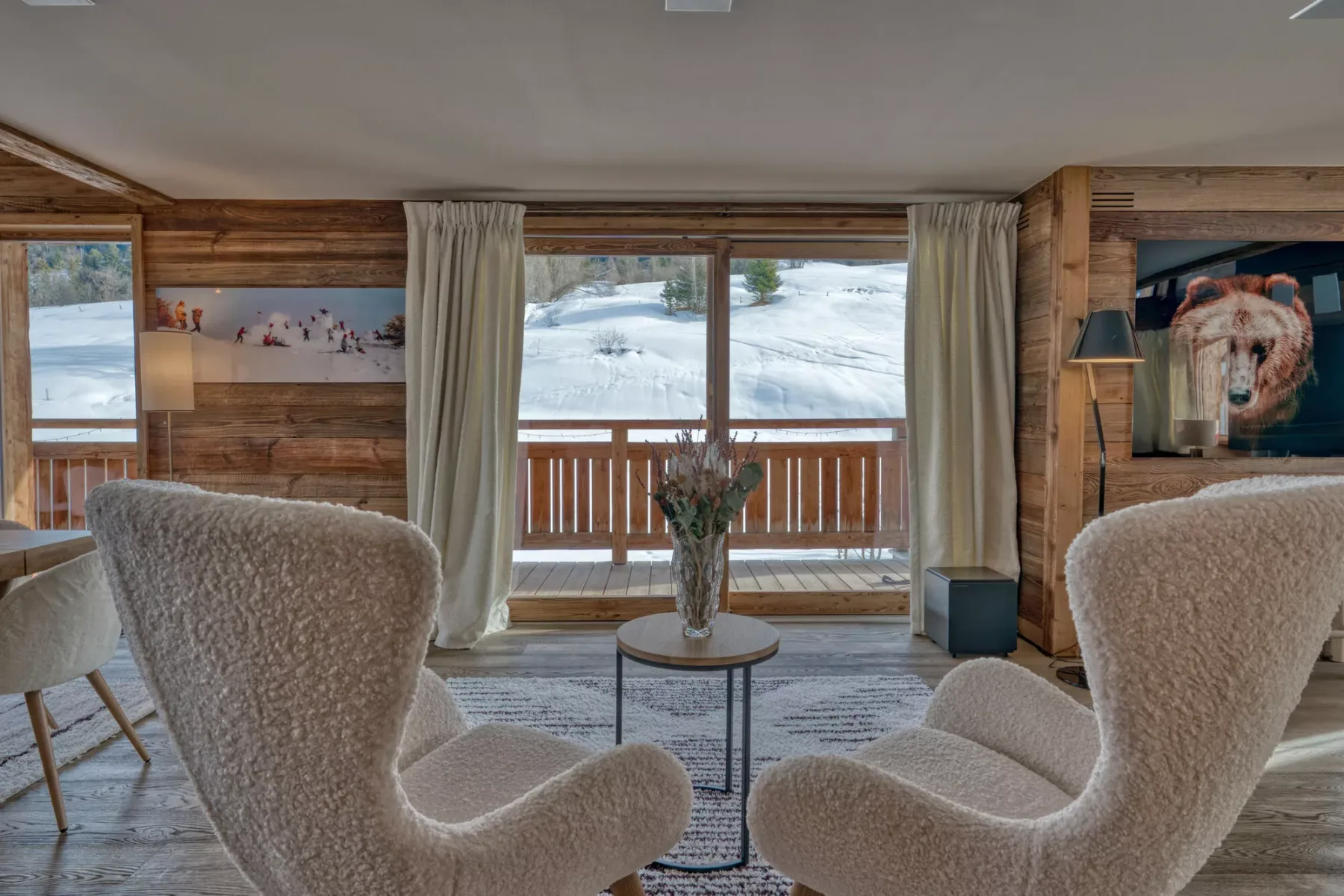 A living room with two upholstered seats facing windows overlooking a snowy landscape.