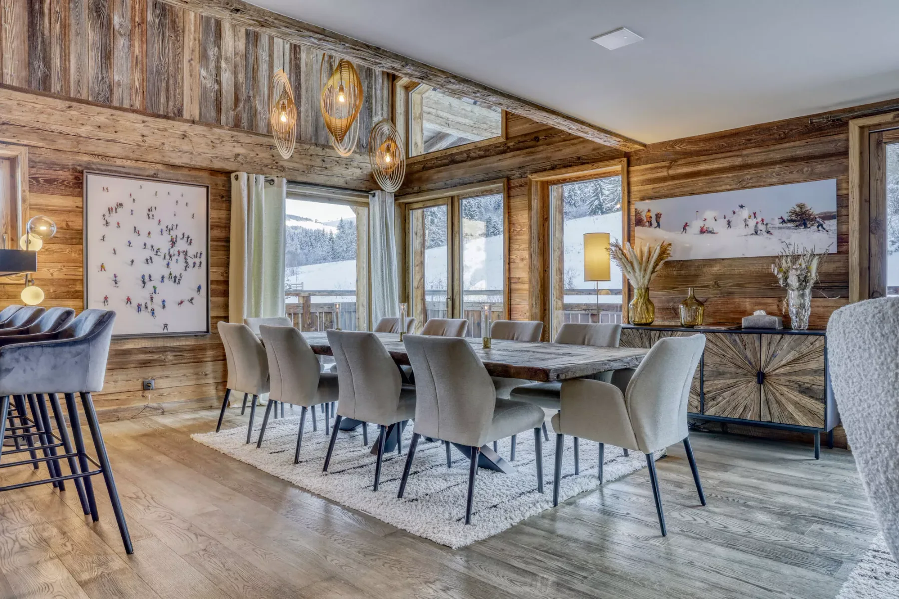 Comedor revestido de madera con una mesa larga y sillas junto a grandes ventanales.