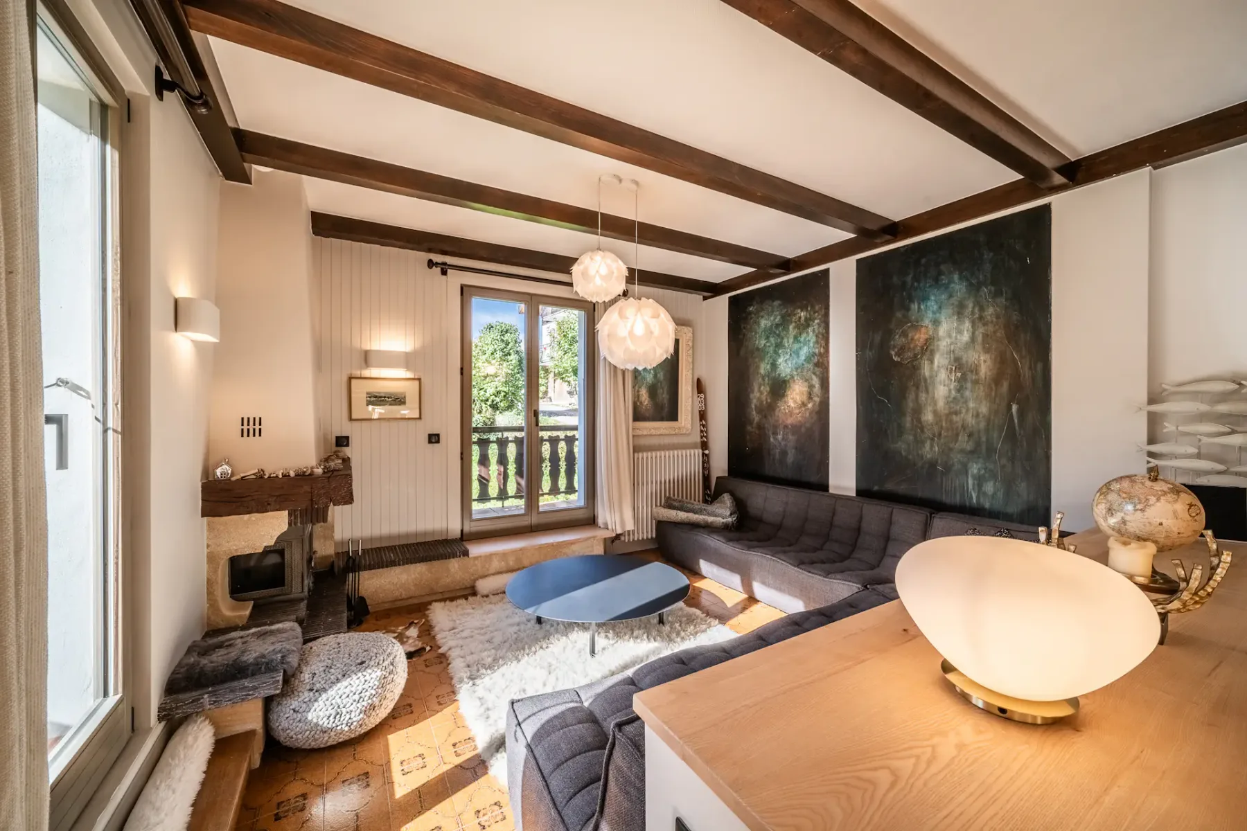 Un salón con un sofá seccional oscuro, una mesa de centro y una gran obra de arte mural.
