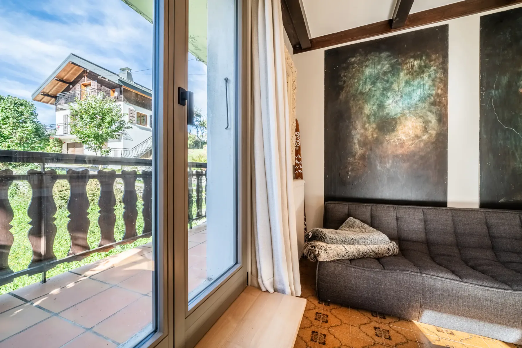Un salón con asientos junto a puertas de cristal que dan a un balcón.