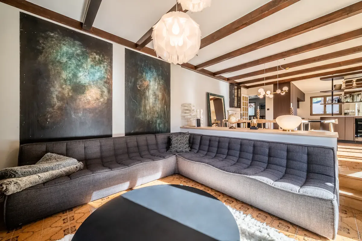 Una sala de estar con un amplio sofá seccional y obras de arte en la pared.