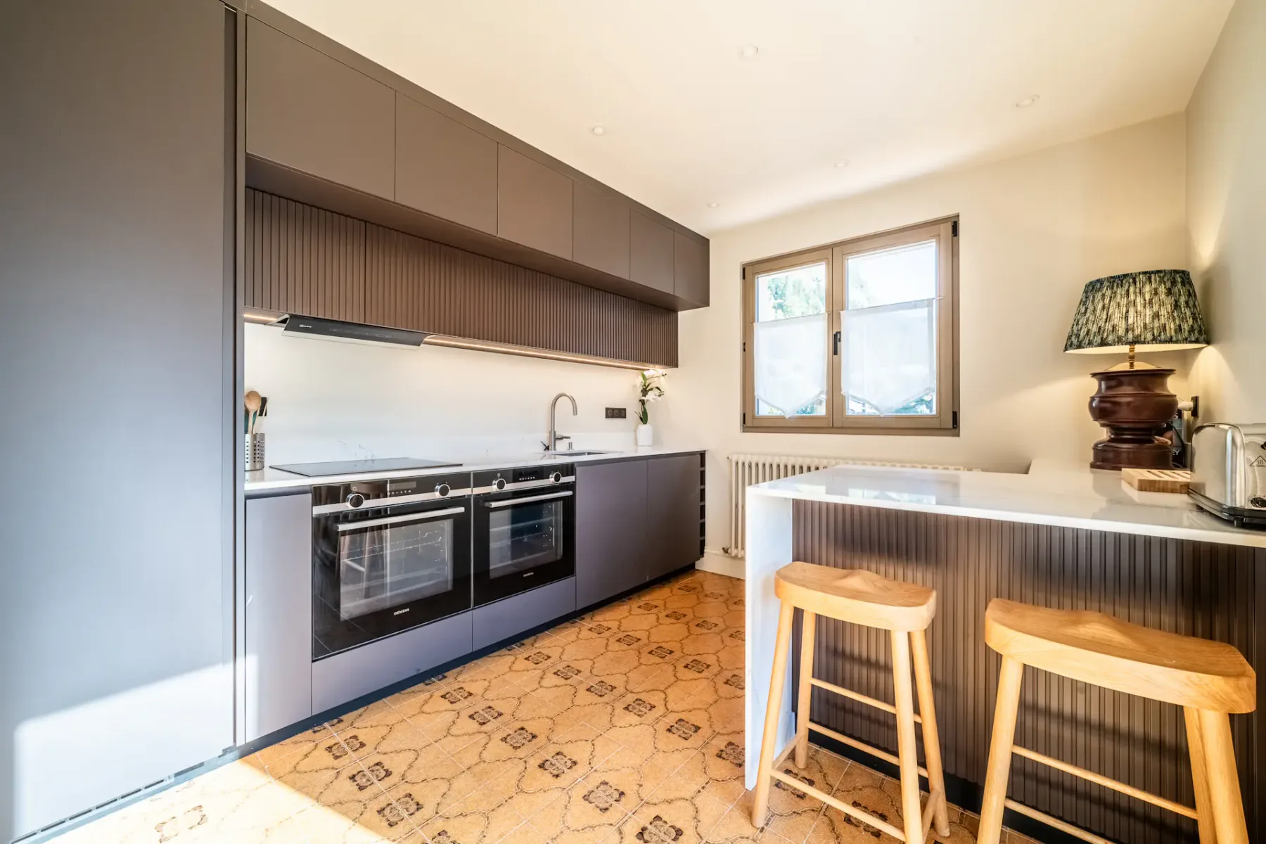 Cocina contemporánea con armarios oscuros, un horno y una barra.