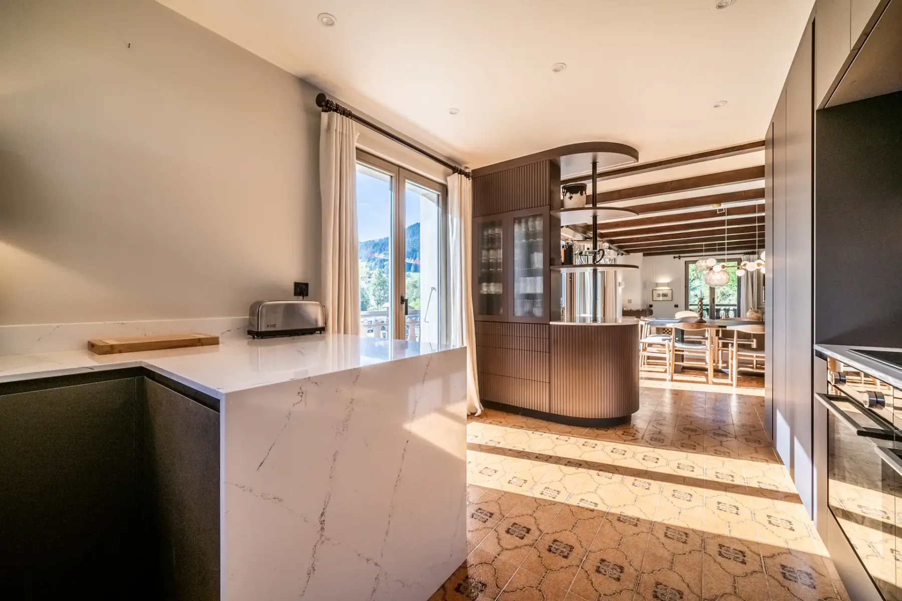 Una cocina moderna con una encimera clara se abre a un comedor.