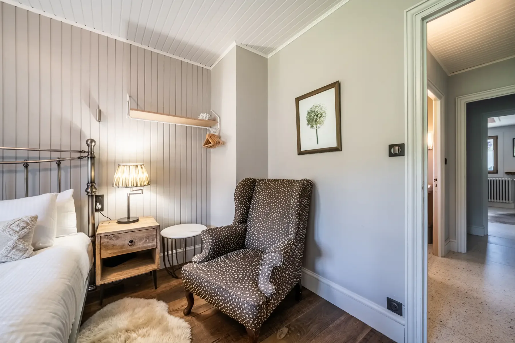 Dormitorio con cama, mesita de noche y sillón estampado.
