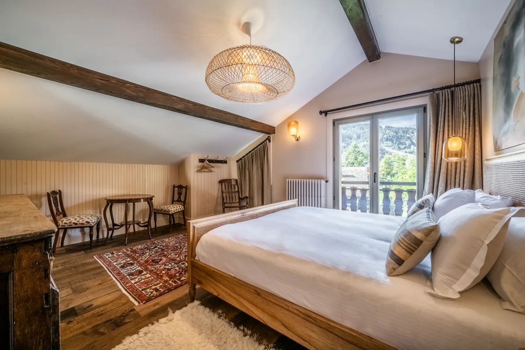 Un dormitorio con una cama grande, una zona de estar y puertas al balcón.