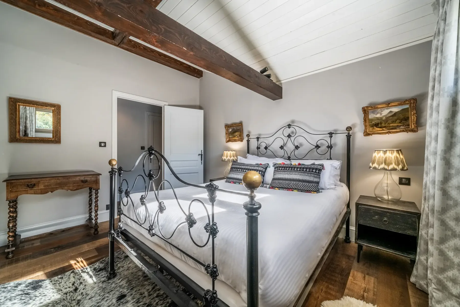Un dormitorio con una cama de metal, mesitas de noche y techo inclinado.