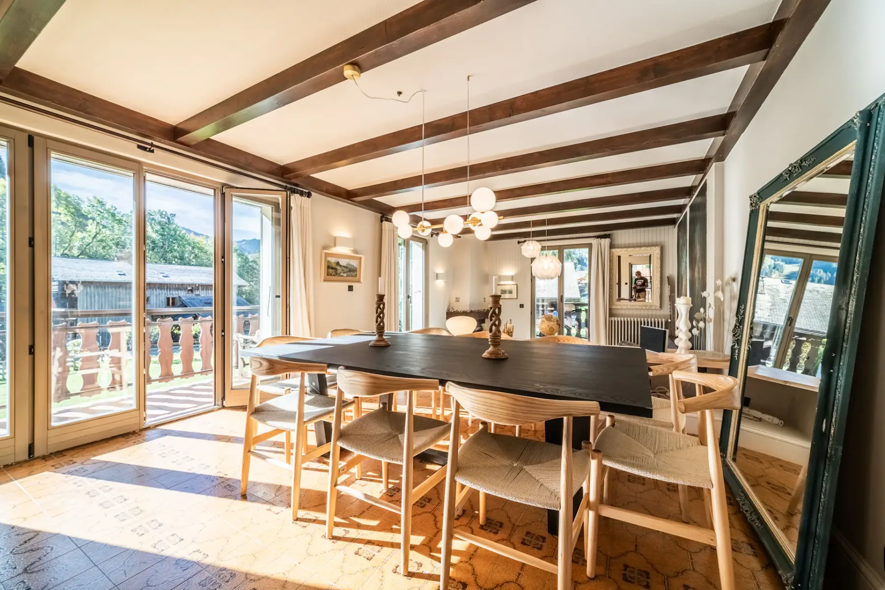 Un comedor con una mesa larga y sillas está junto a grandes ventanas.