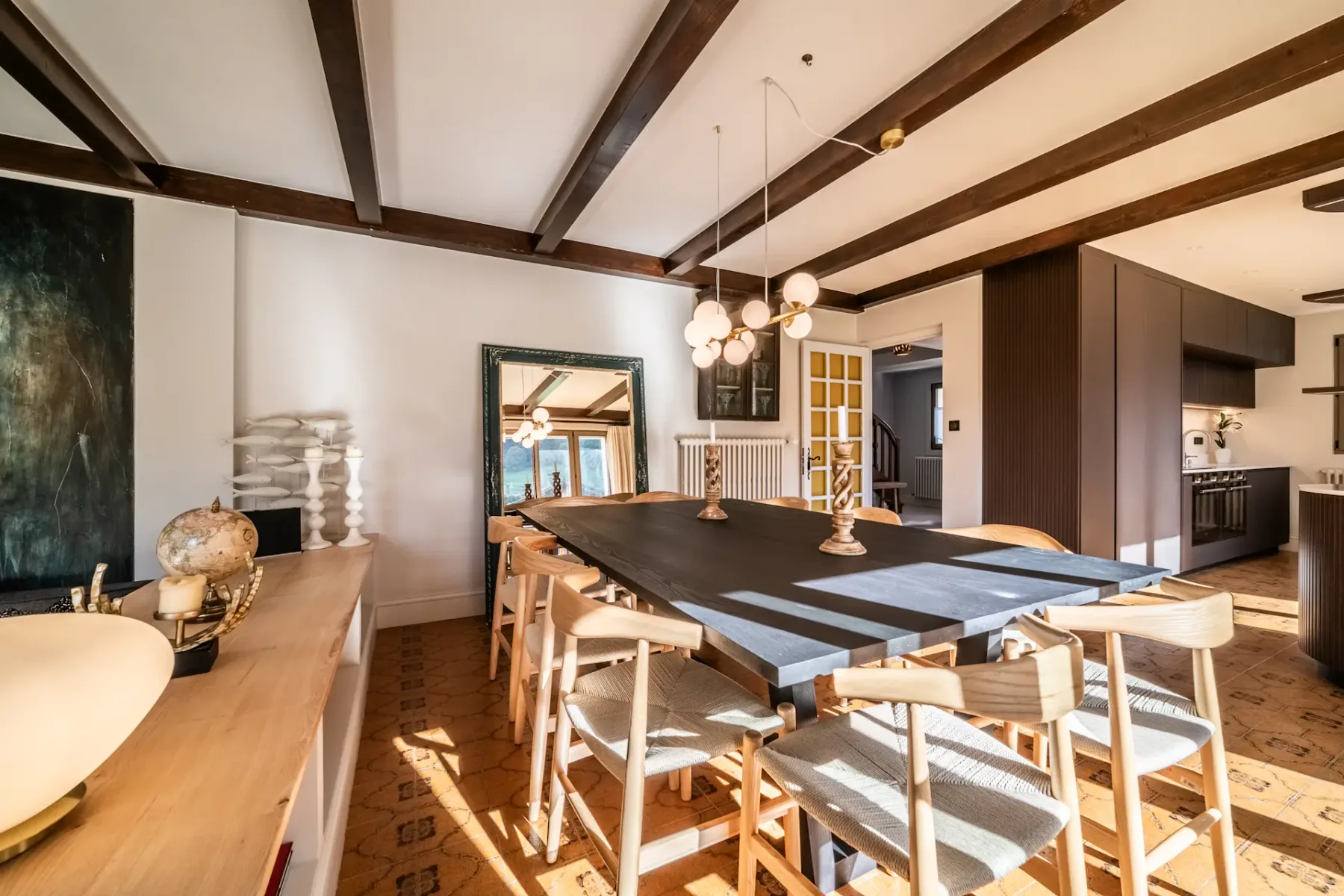 Comedor con una mesa larga y asientos de madera bajo vigas de techo expuestas.