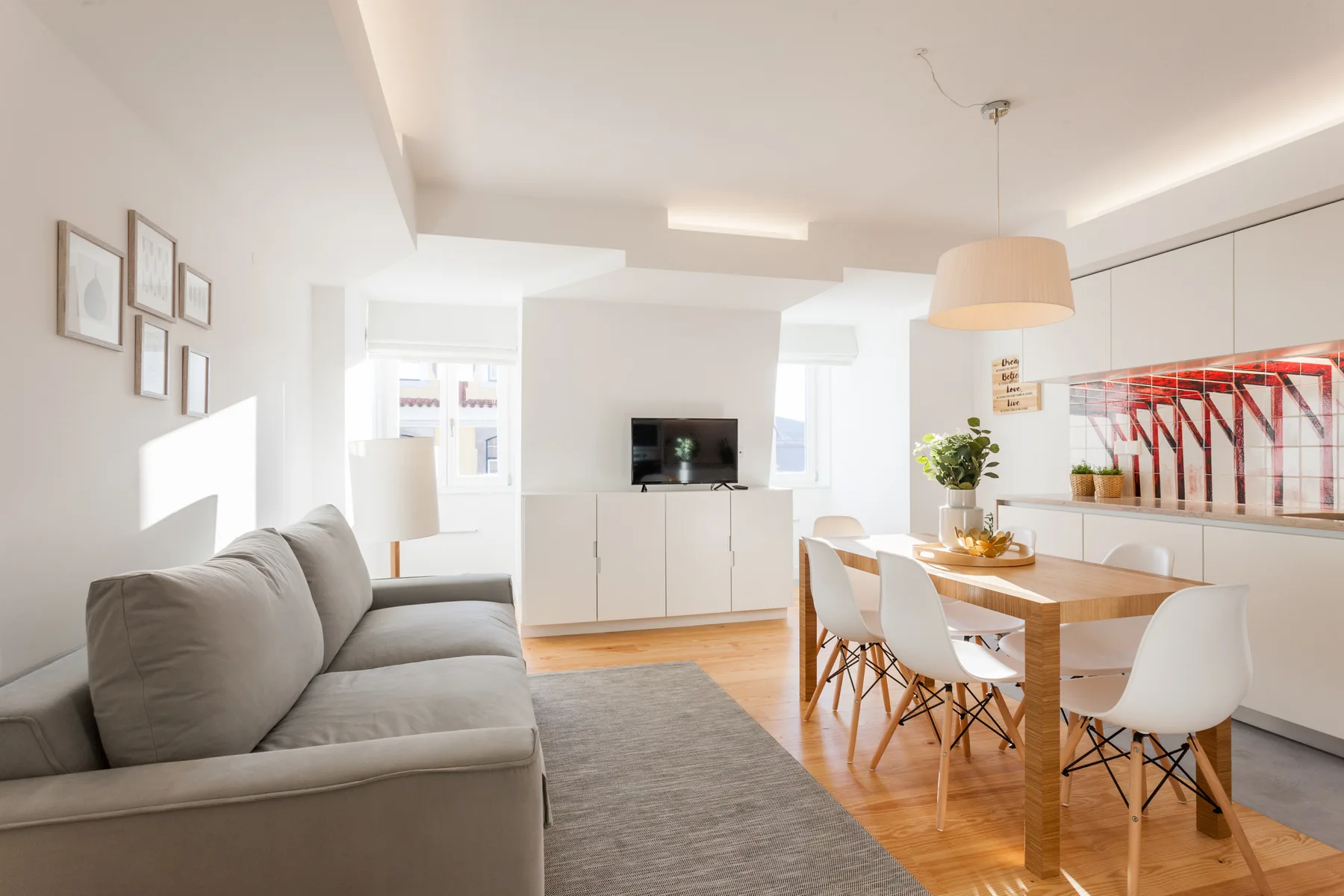 Bright living and dining area with a sofa, television, and wooden dining table.